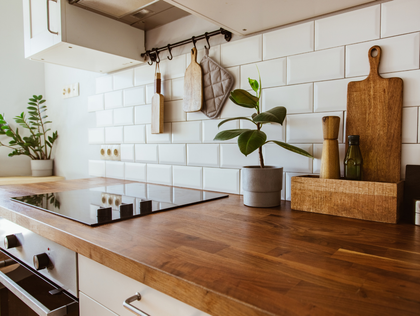 Wooden countertop in bright kitchen with white subway tile backsplash and plants.