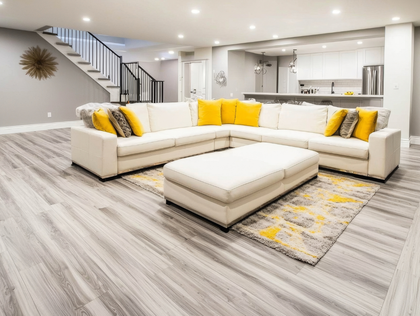 Spacious, modern living room with sectional sofa, ottoman, and kitchen in the background. Light gray and yellow accents.