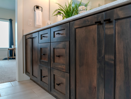 Dark stained wood bathroom vanity with drawers and cabinets; white countertop.