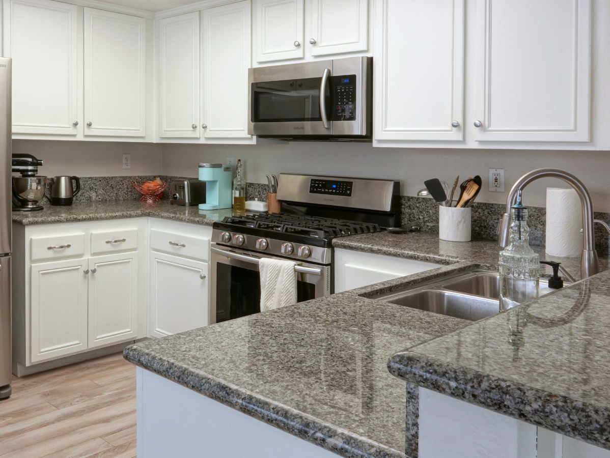 White kitchen with granite countertops and stainless steel appliances.