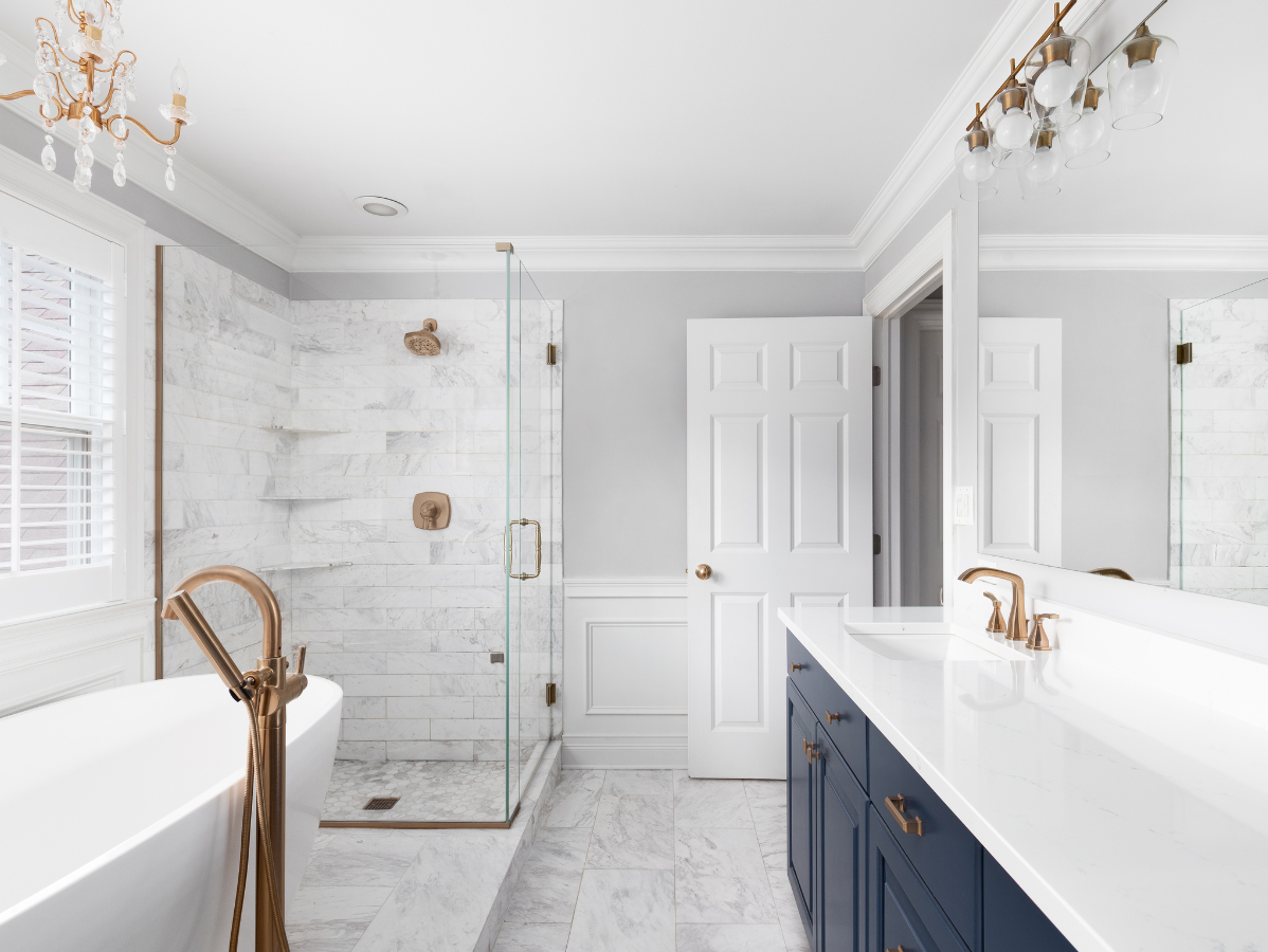 Luxurious bathroom with a blue vanity, marble shower, and gold fixtures.