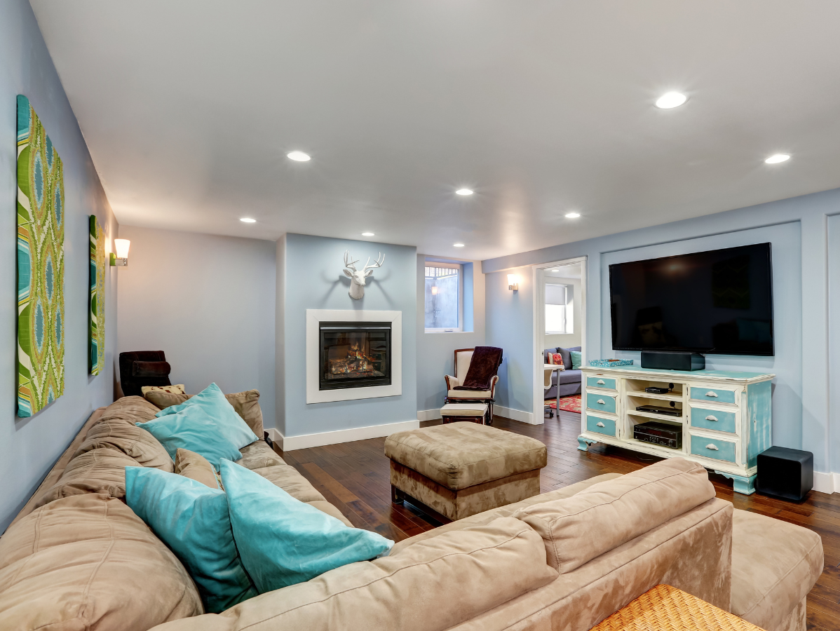 Cozy living room with blue walls, fireplace, TV, large sofa, and teal pillows.