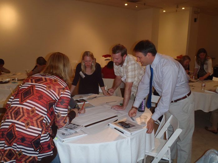 A group of people are gathered around a table with papers on it