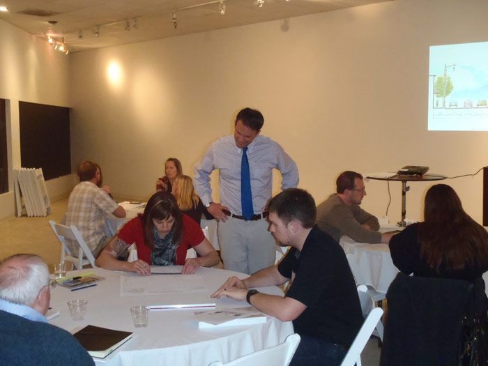 A man in a blue tie stands in front of a group of people