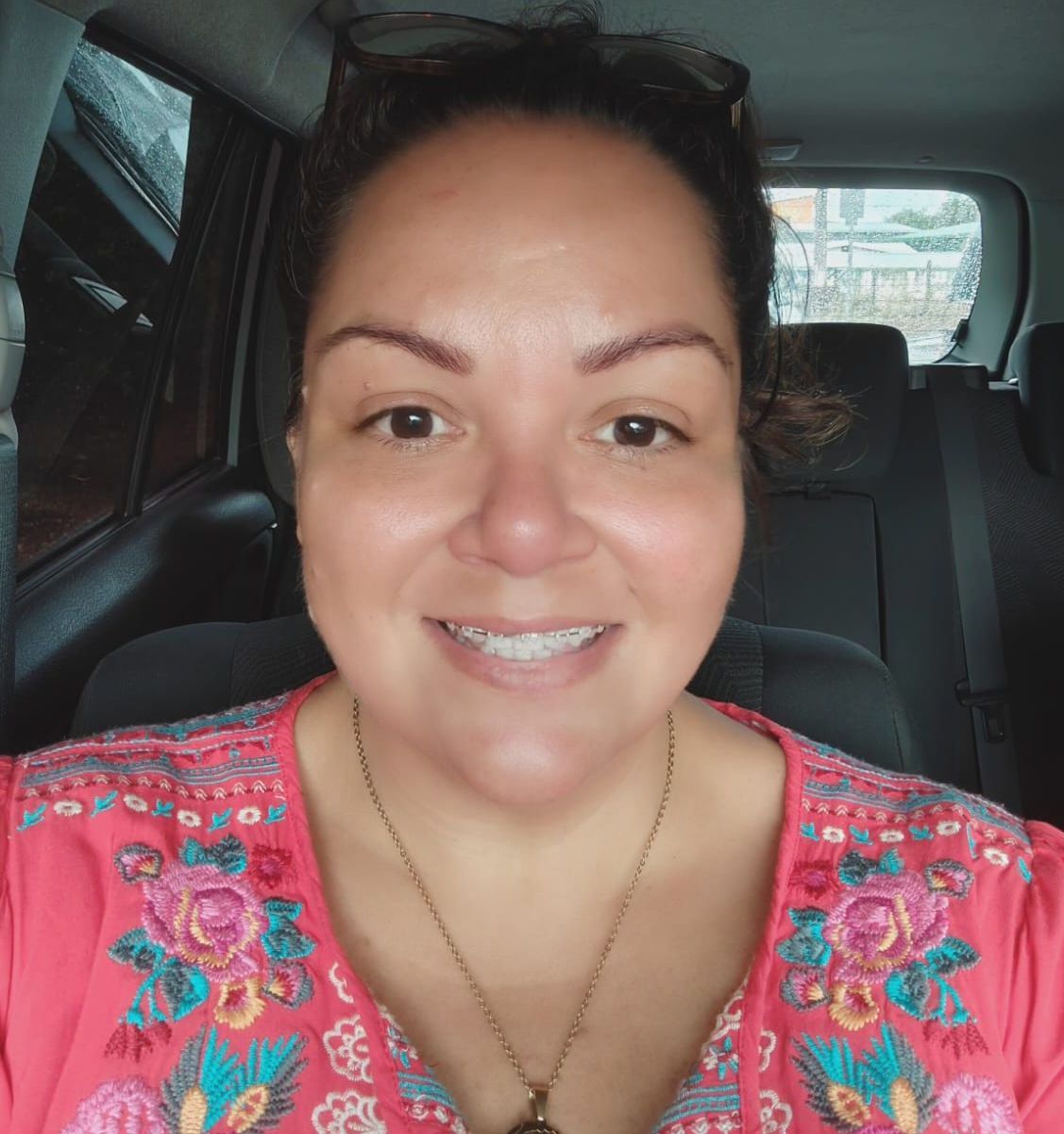 A woman is smiling while sitting in the back seat of a car