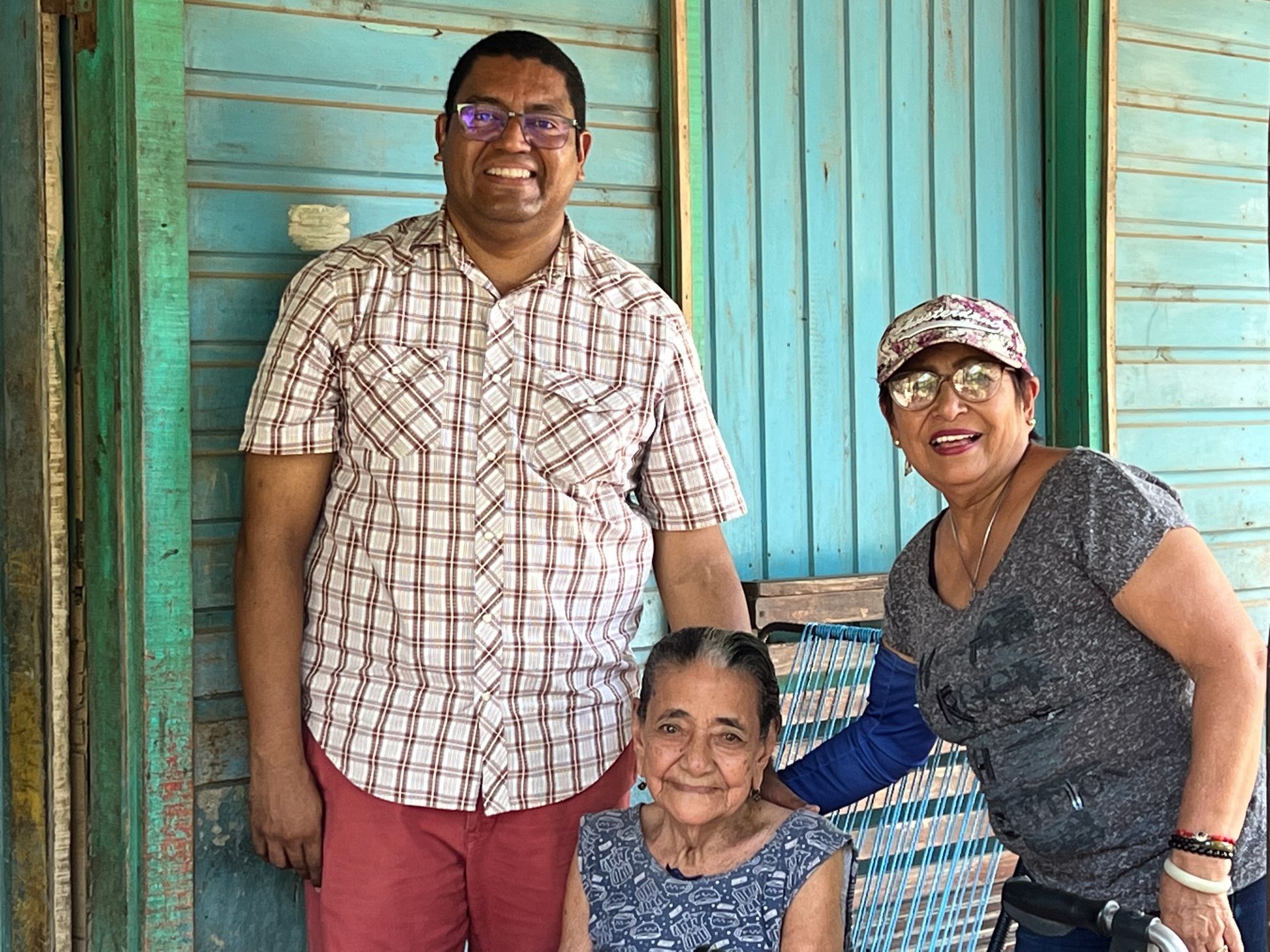 A man and two women are posing for a picture in front of a blue building.