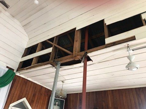 A room with a ceiling fan and wooden walls.