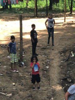 A group of children are standing in a dirt area.