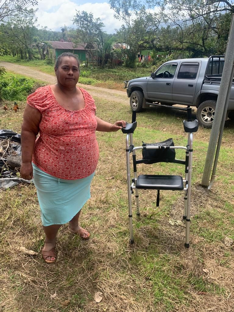 A woman is standing next to a walker in a field.
