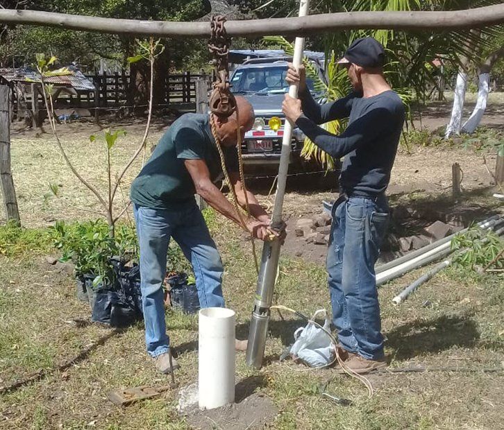 Two men are working on a pipe in a field