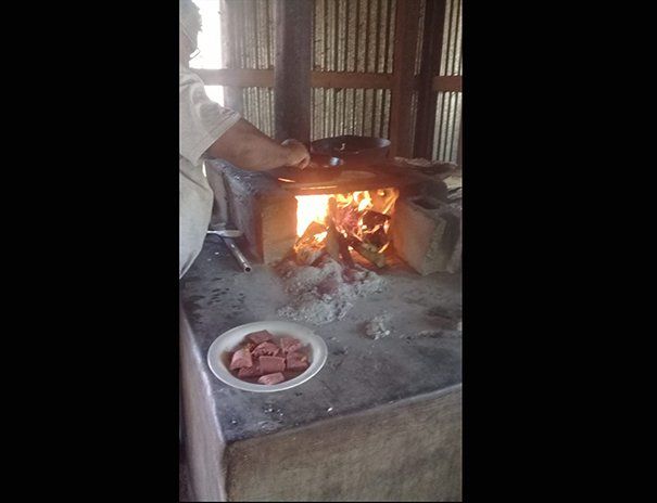 A person is cooking food on a stove with a plate of food on the table.