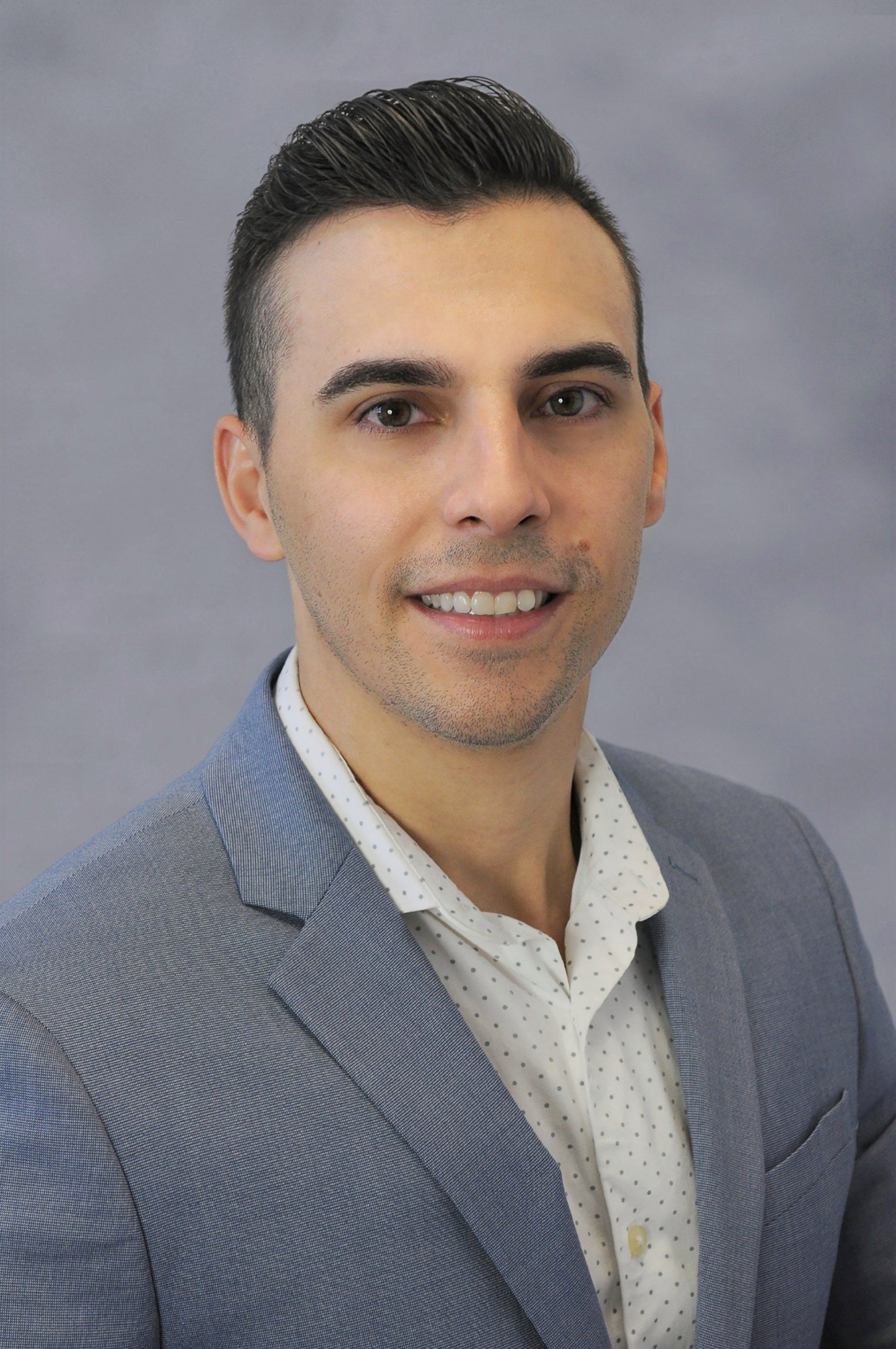 A man in a suit and white shirt is smiling for the camera.