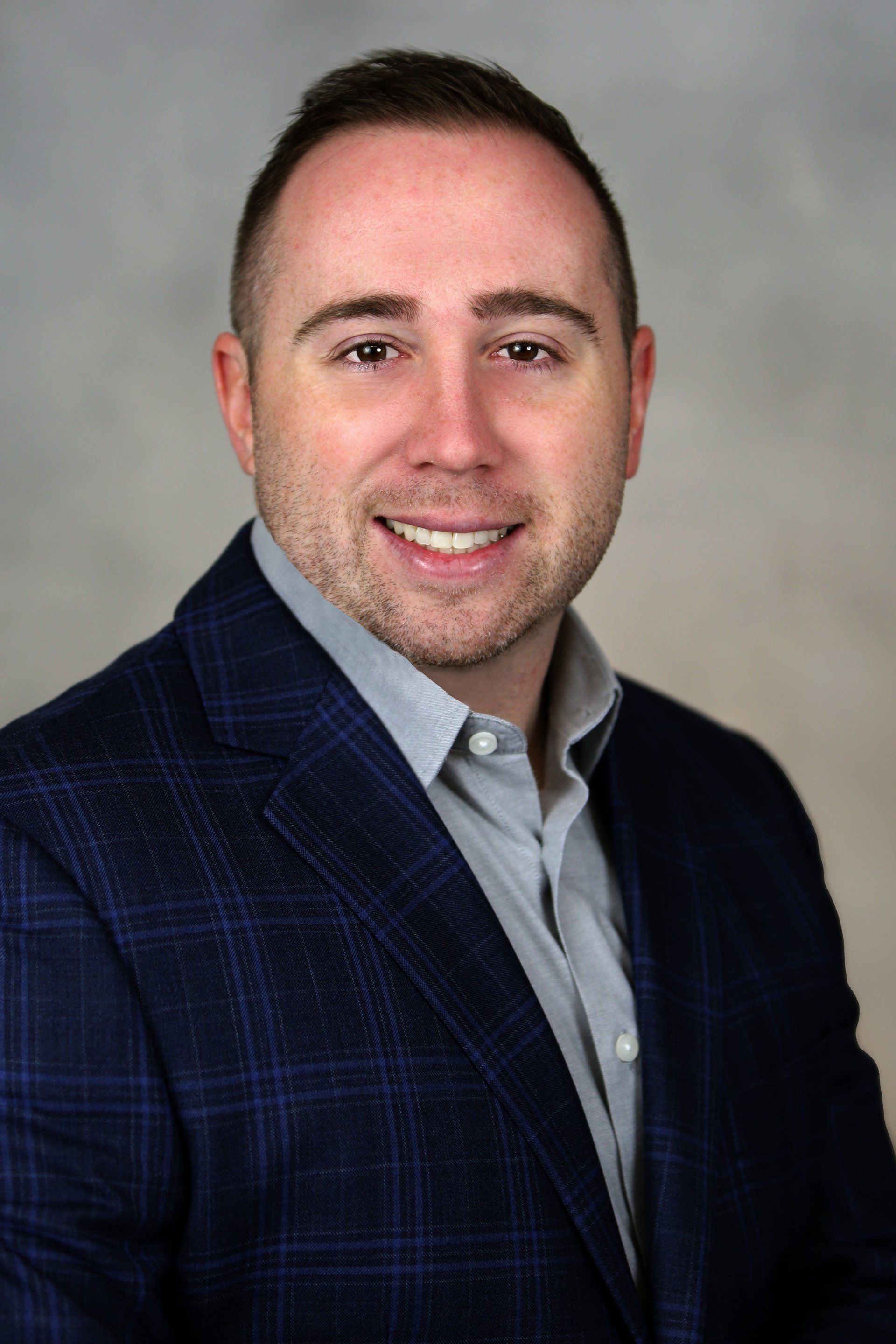 A man in a suit and shirt is smiling for the camera.