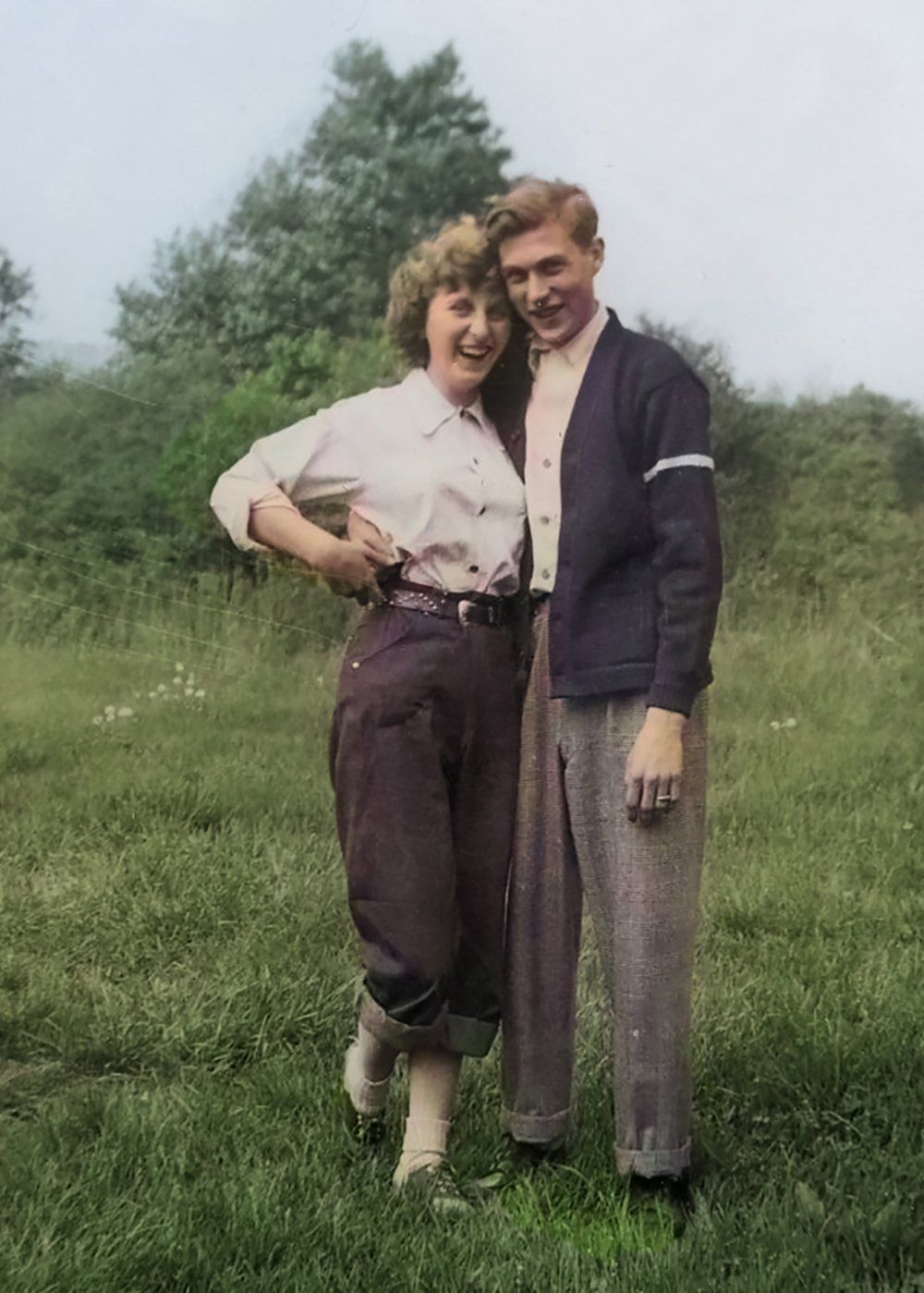 A man and a woman are posing for a picture in a field.