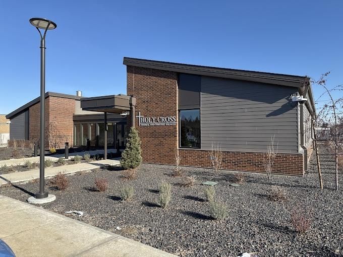 A modern, one-story brick and grey siding office building with a small landscaped rock garden under a clear blue sky.