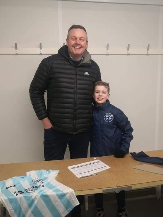 A man and a boy are posing for a picture in a dressing room