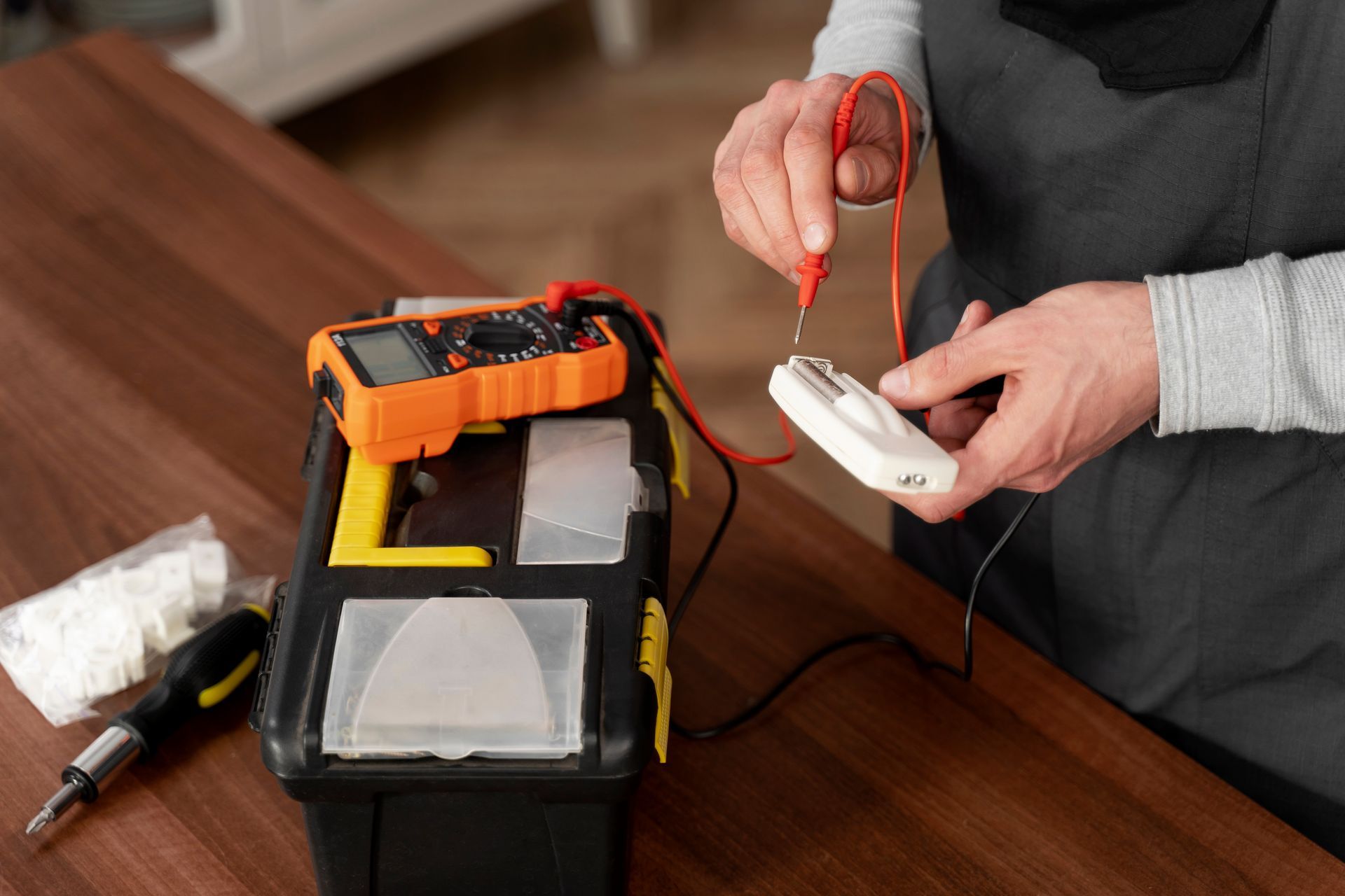 A person is fixing a remote control with a multimeter.