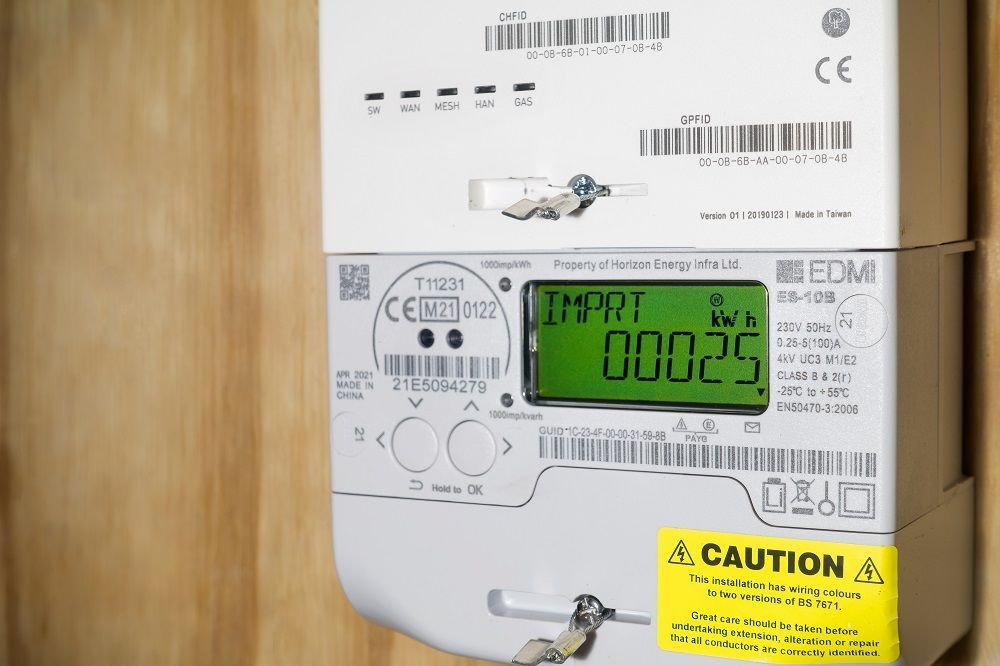 A close up of a digital electricity meter on a wooden wall.