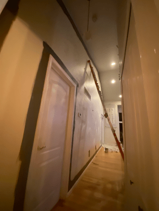 A long hallway with a ladder hanging from the ceiling