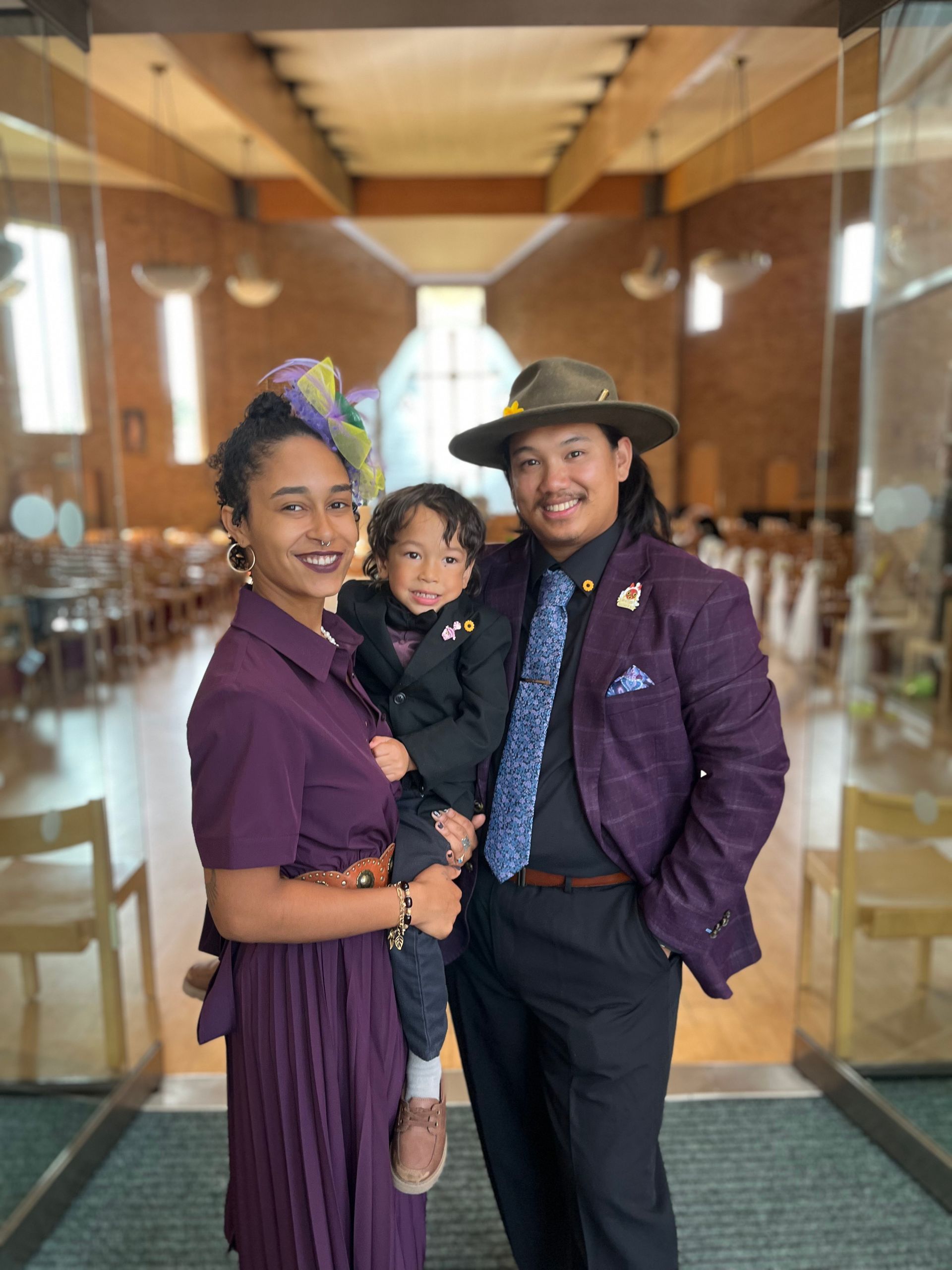 A man and two children are standing in front of a graffiti covered wall.