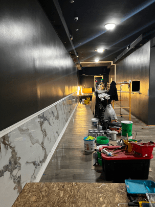 A long hallway is being painted in a building.