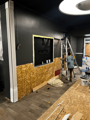 A man is standing on a ladder in a room.