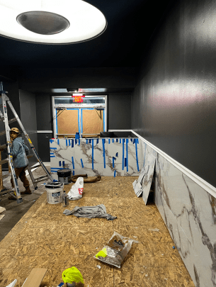A man is standing on a ladder in a room that is being remodeled.