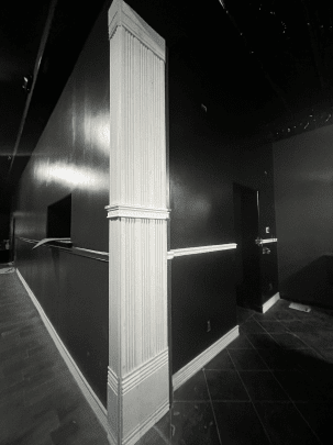 A black and white photo of a hallway with black walls and white trim