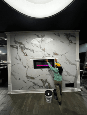 A woman is hanging a fireplace on a marble wall.
