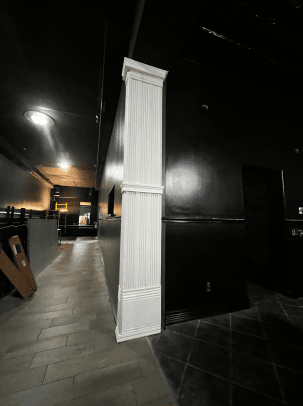 There is a white column in the middle of a hallway.