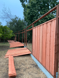 A wooden fence is being built in a backyard.
