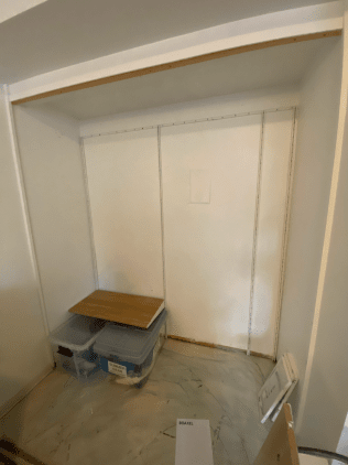 A closet with a wooden table and plastic bins in it.