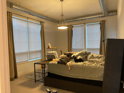 A bedroom with a bed , a table , and a lamp.