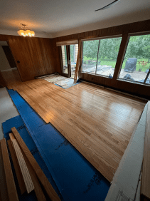 A living room with a wooden floor and lots of windows.