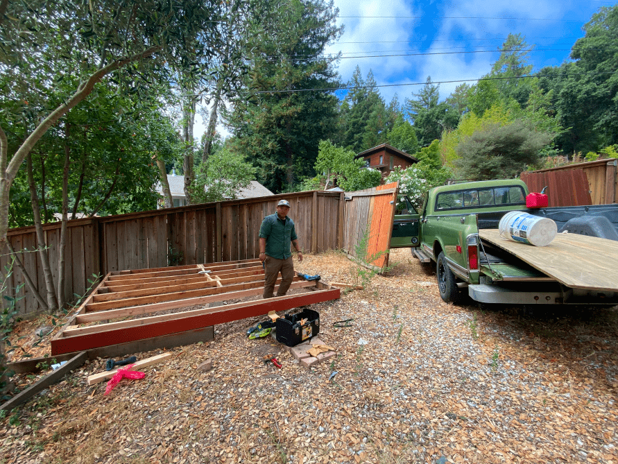 A man is standing in a yard next to a truck.