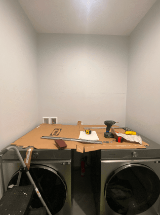 A laundry room with two washing machines and a cardboard box on the floor.