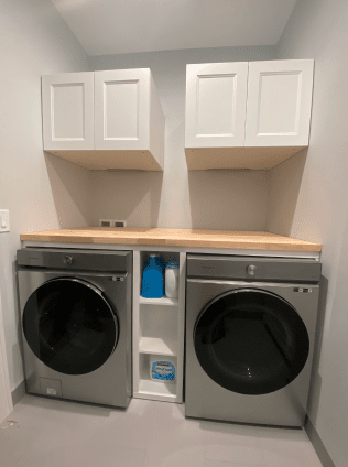A laundry room with two washers and dryers and white cabinets.