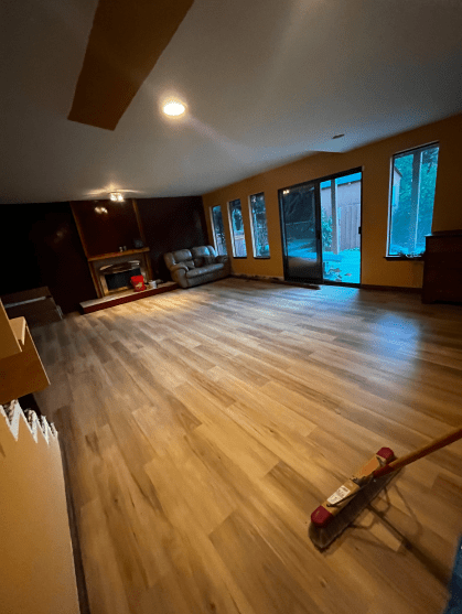 A person is cleaning the floor of a living room with a broom.