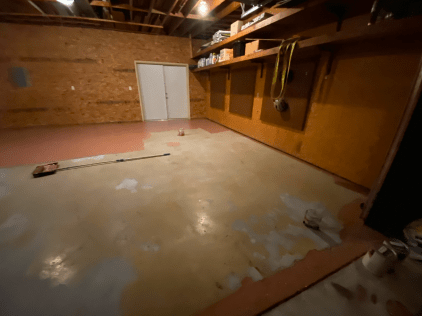 An empty basement with a broom on the floor