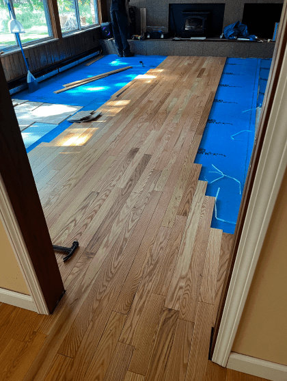 A wooden floor is being installed in a living room.
