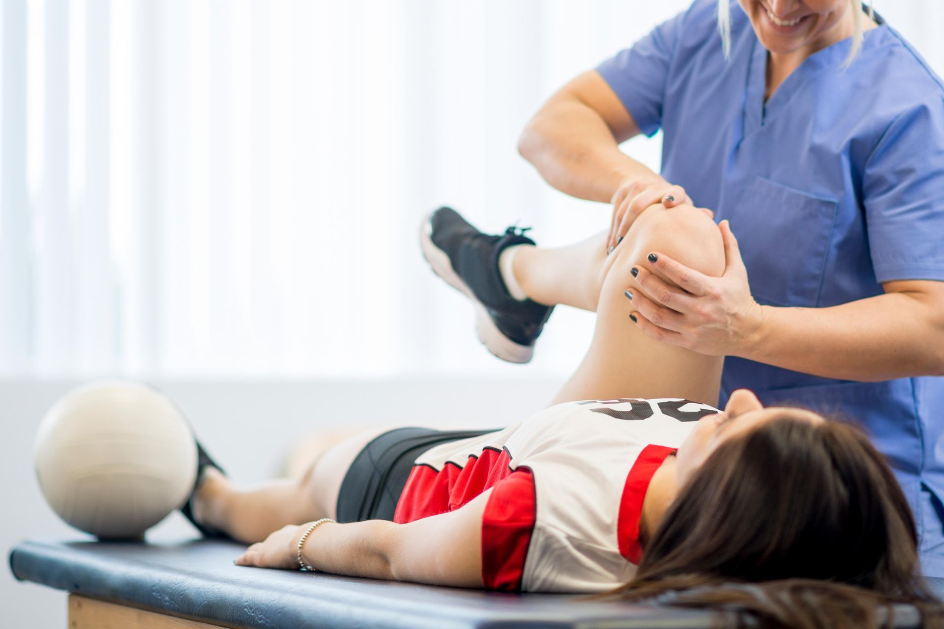 A female high school volleyball player is sitting at the doctors office to get a look at her injury.