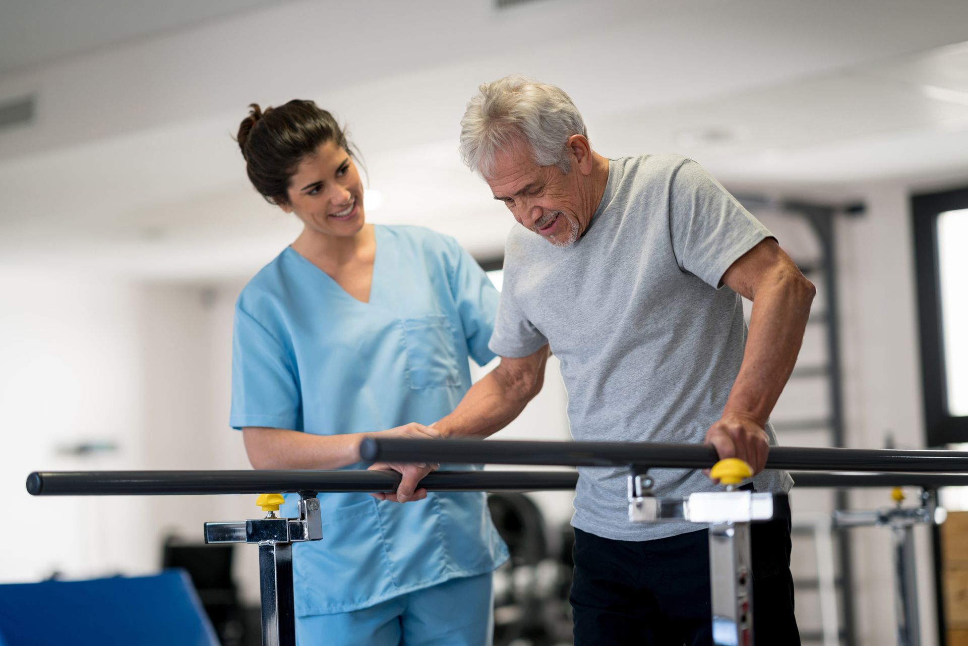 Occupational therapist and senior patient working out using parallel bars to walk. Occupational therapist and senior patient working out using parallel bars to walk.