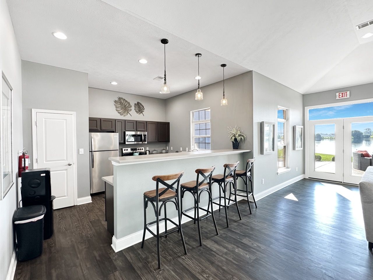 Open-concept kitchen with bar seating, stainless steel appliances, and dark wooden floors.