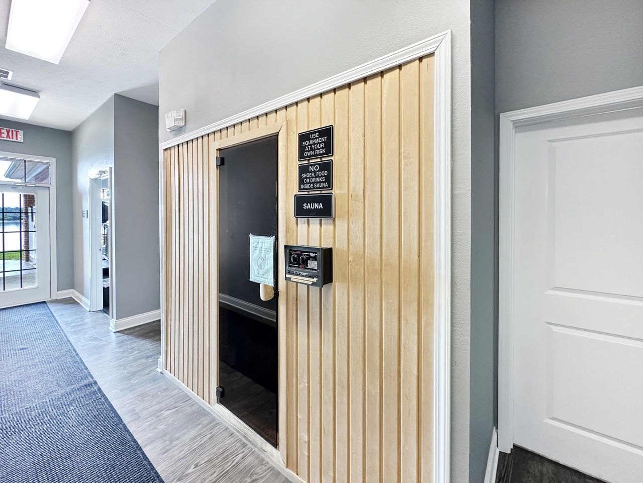 Hallway with light wood paneling and chalkboard, white door to the right.