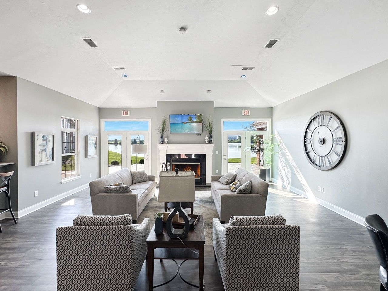 Spacious living room with gray sofas, fireplace, TV, and large clock.