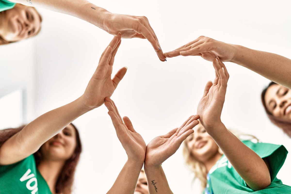 A group of volunteers are making a heart shape with their hands