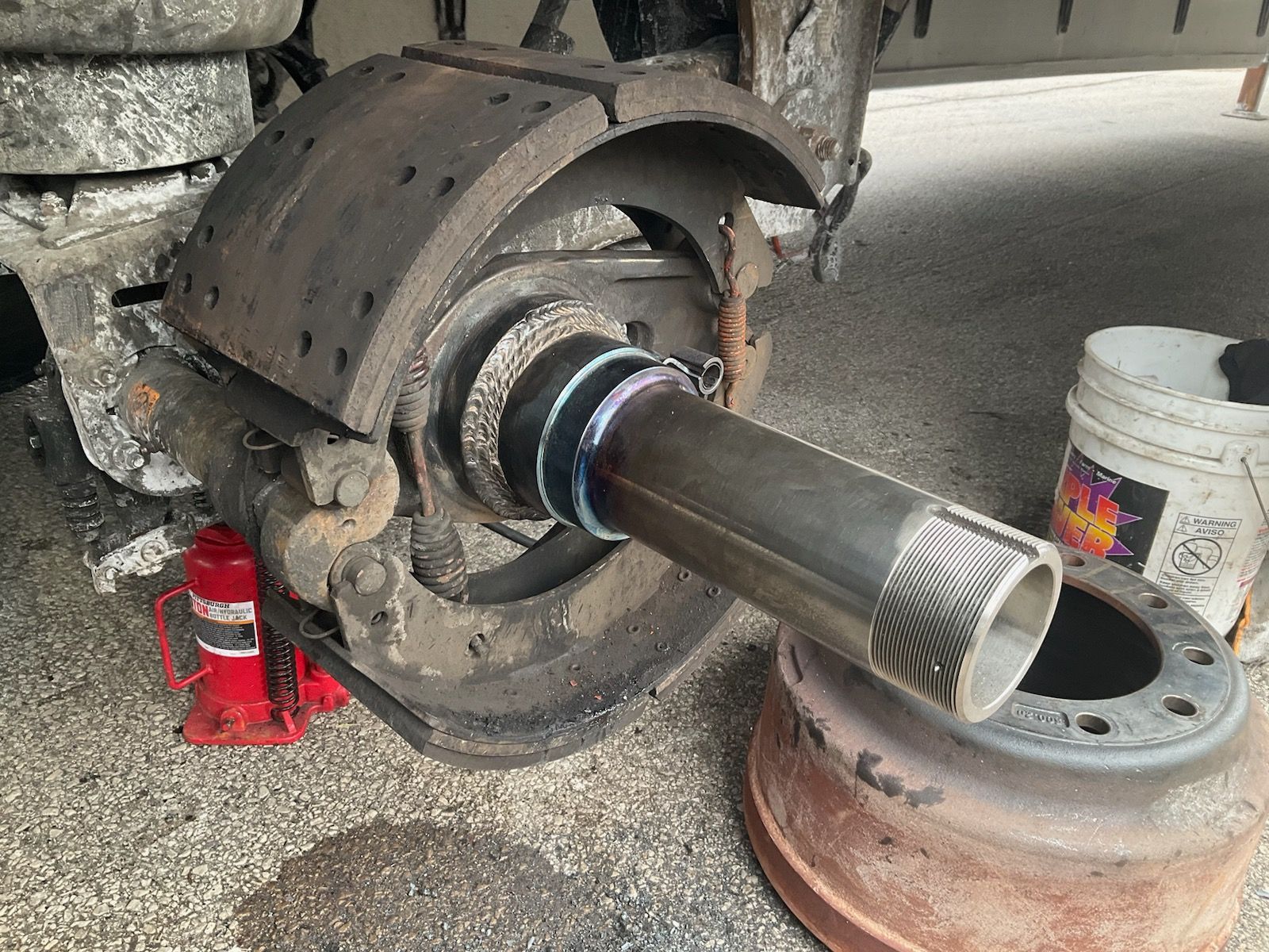 Truck wheel hub with detached brake components. Silver metal axle and dark brake drum visible.