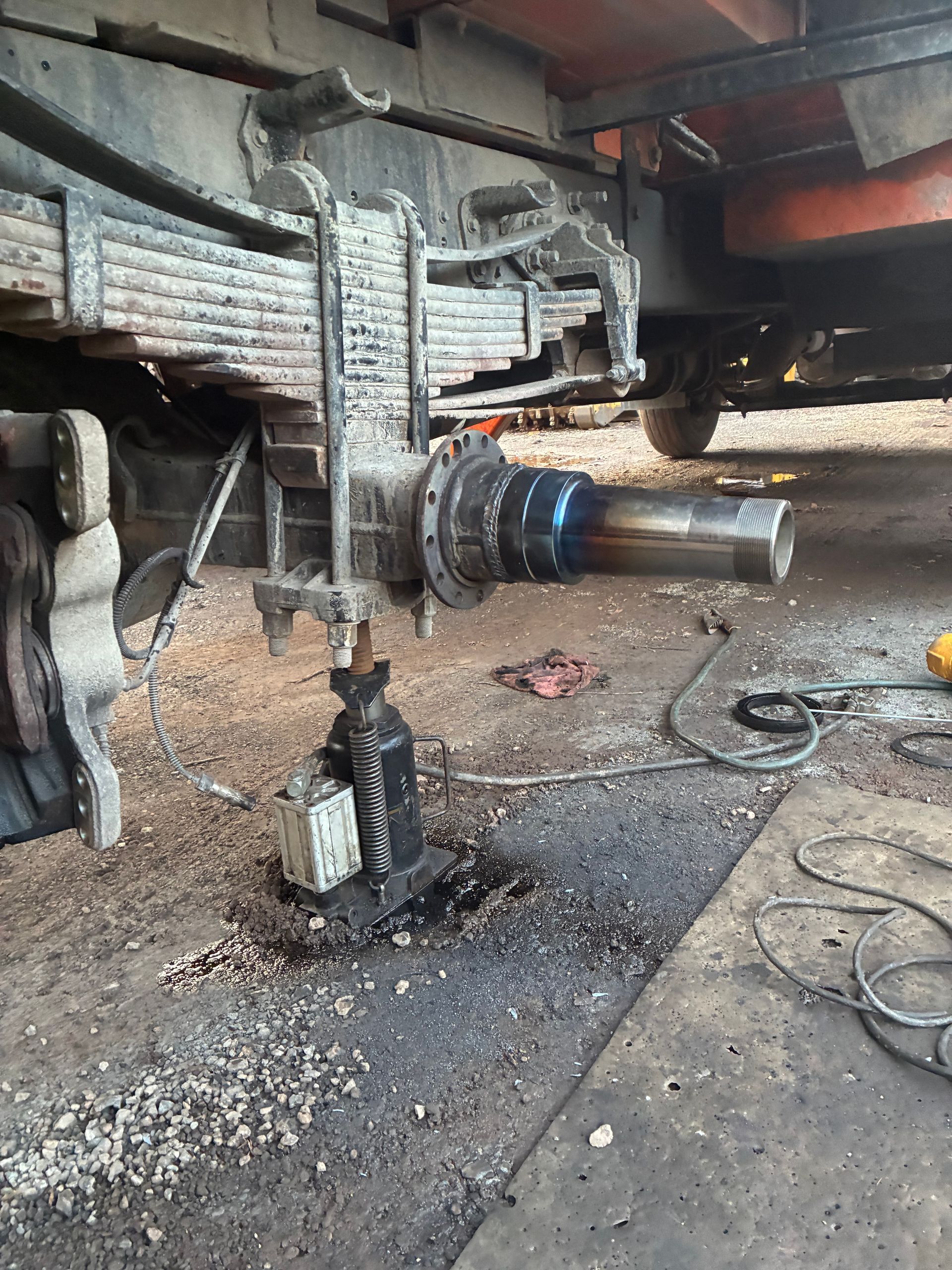 Truck wheel assembly being repaired with jack underneath.