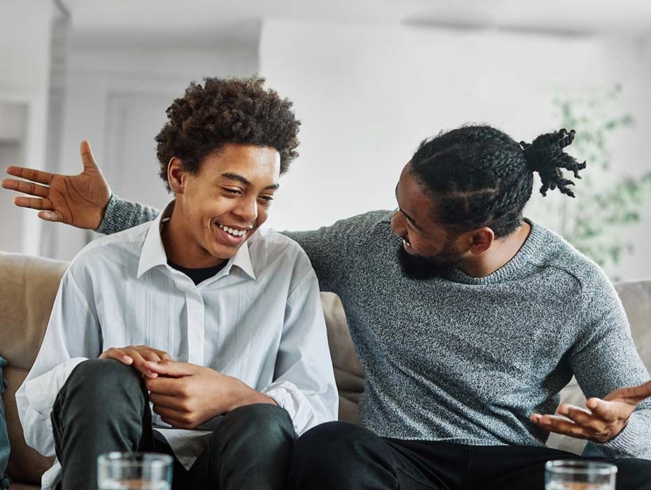 A woman and a boy are sitting on a couch with their arms crossed.