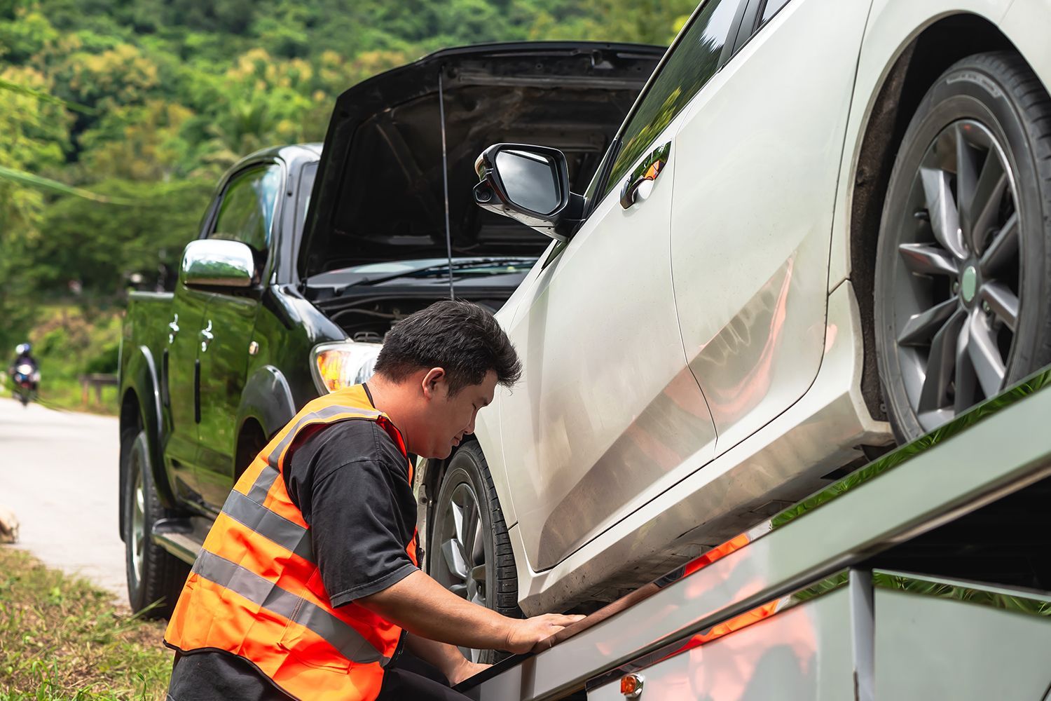 A vehicle towing professional securing a car on a tow truck for safe roadside vehicle removal.